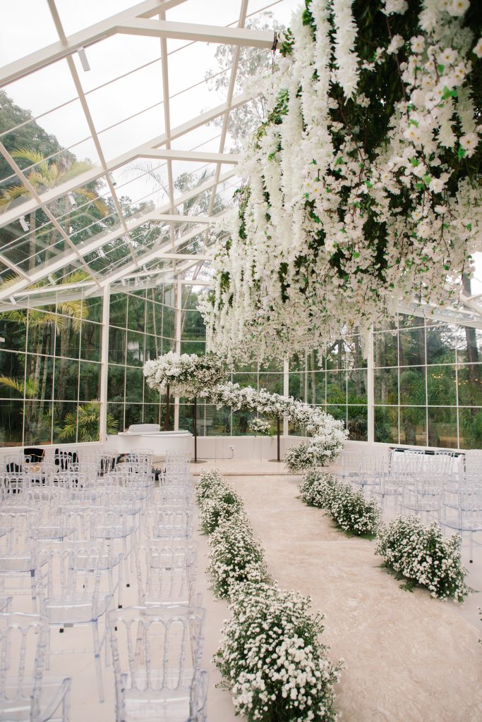 Cerimônia de casamento na capela de vidro do Serra dos Cristais, em Jundiaí, com altar orgânico e flores suspensas integradas à natureza.